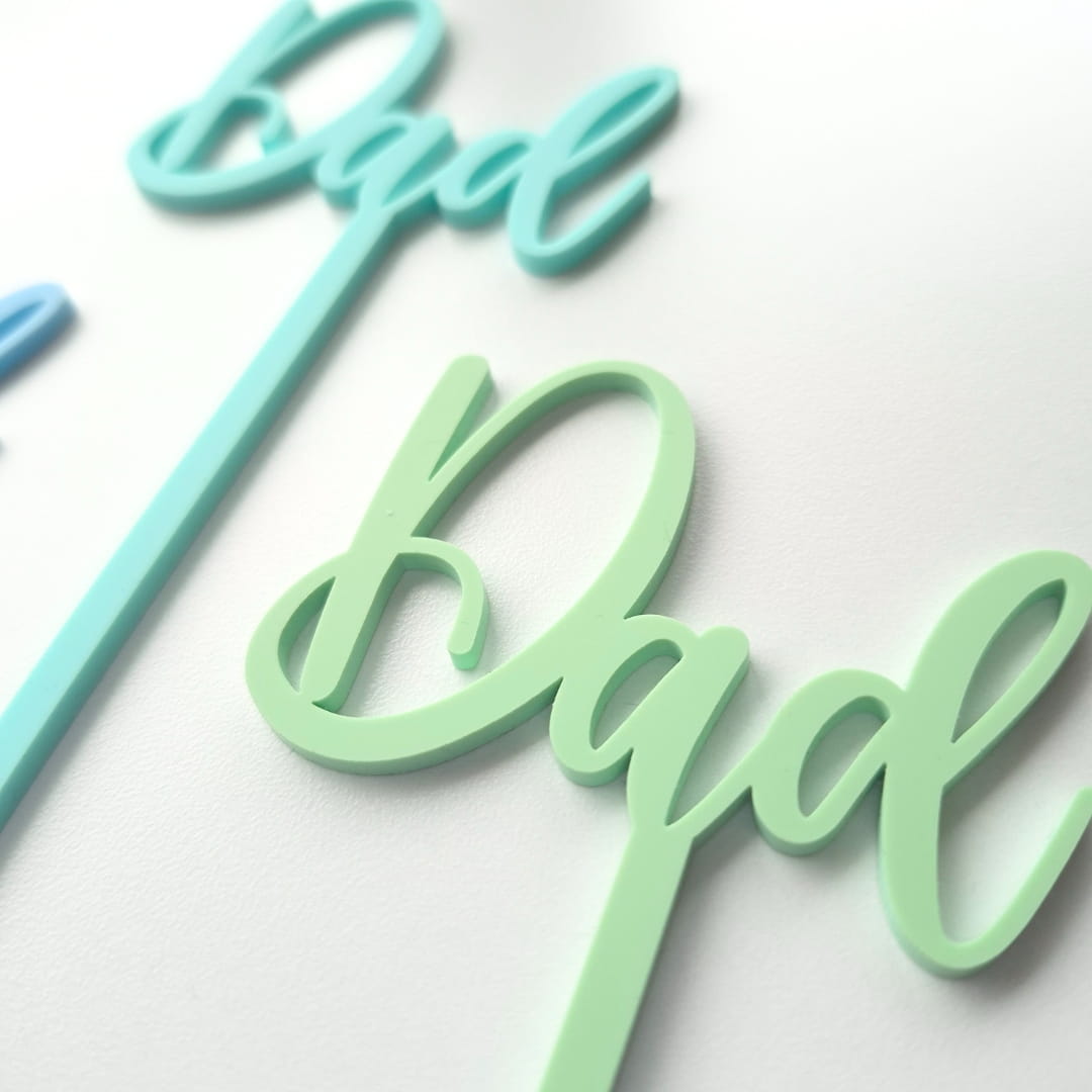 Two 'dad' signs, one in turquoise and one in green, on a white background.