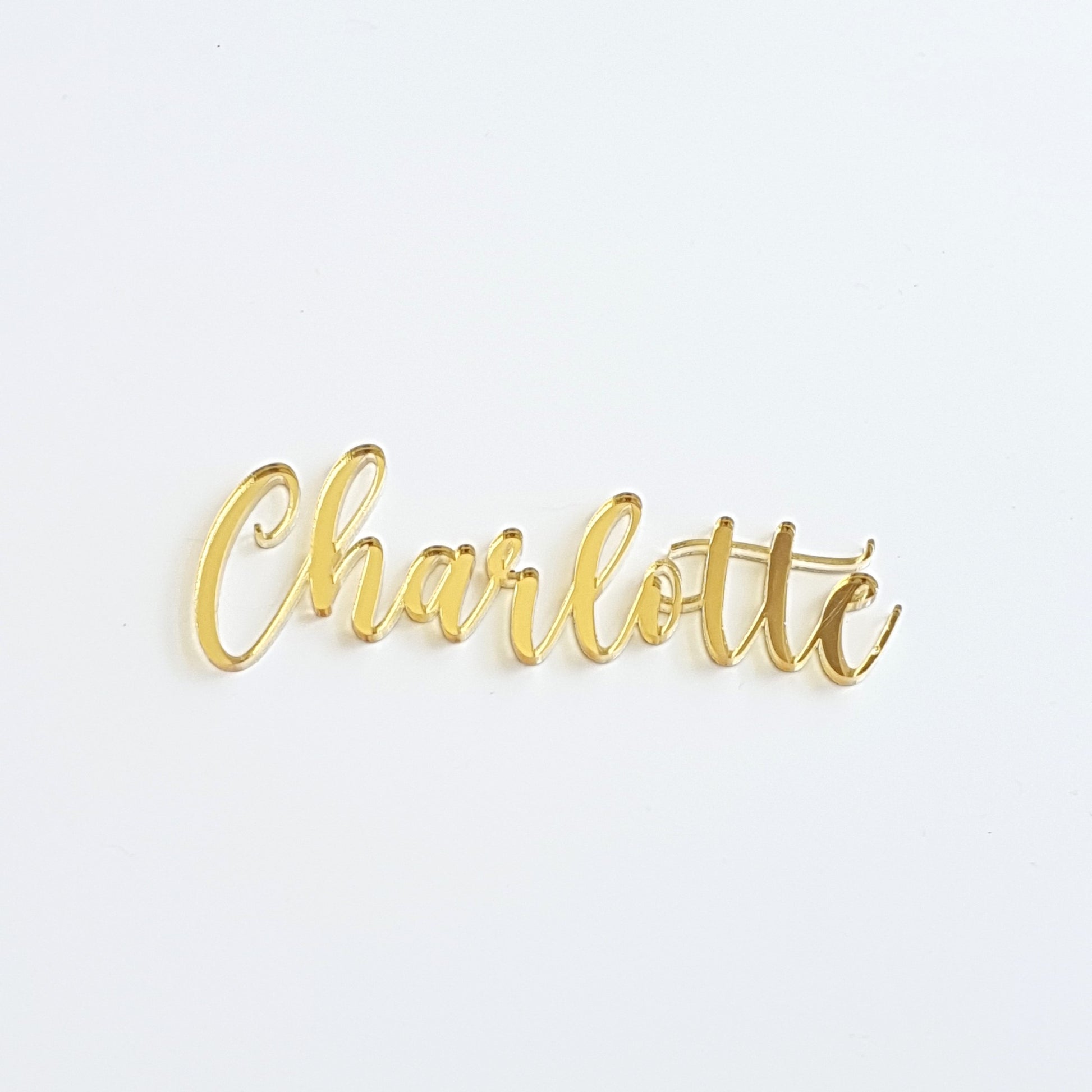 Photo of our acrylic name plaque saying the name Charlotte in script font, made from gold mirror acrylic