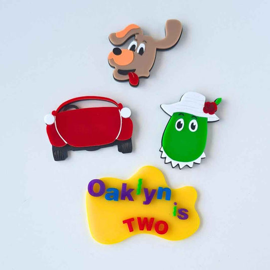 Set of colorful character-themed birthday party favors on a light gray background