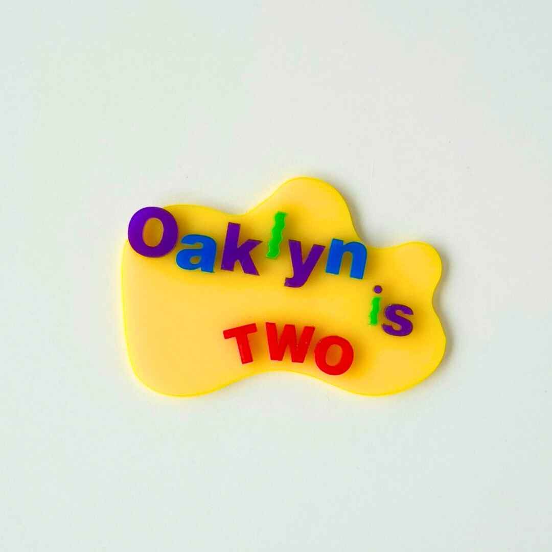 Colorful text 'Oaklyn is TWO' on a yellow background